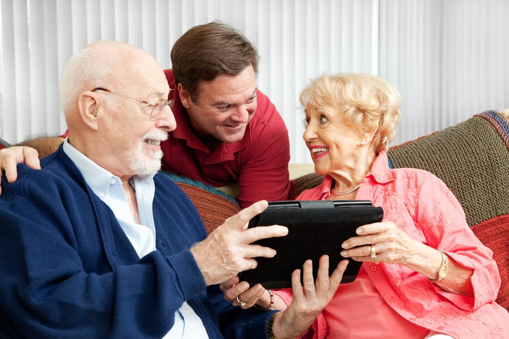 Senior couple get a gift of a tablet PC from their adult son.
