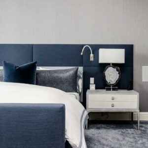white and clear desk lamp on white wooden nightstand near bed