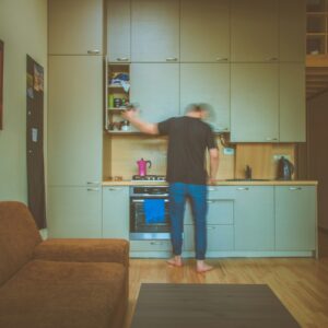 man facing on gray wooden cabinet picking container